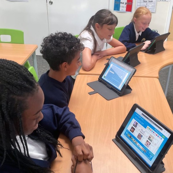 Pupils sitting a desk, using a tablet