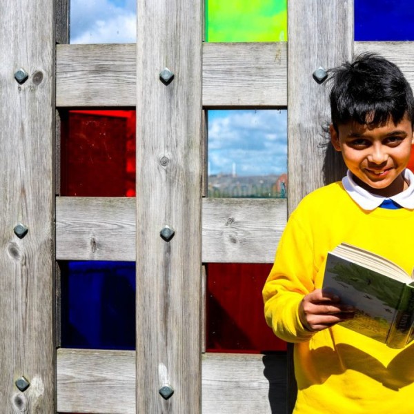 A child wearing a yellow jumper, reading a book