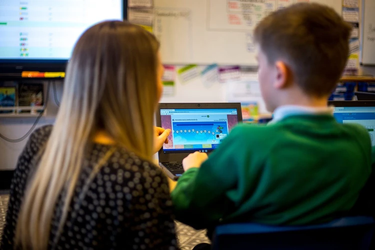 A teacher and pupil using a laptop