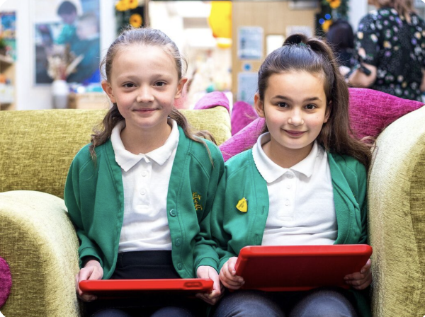 Two girls sitting on a sofa using a tablet