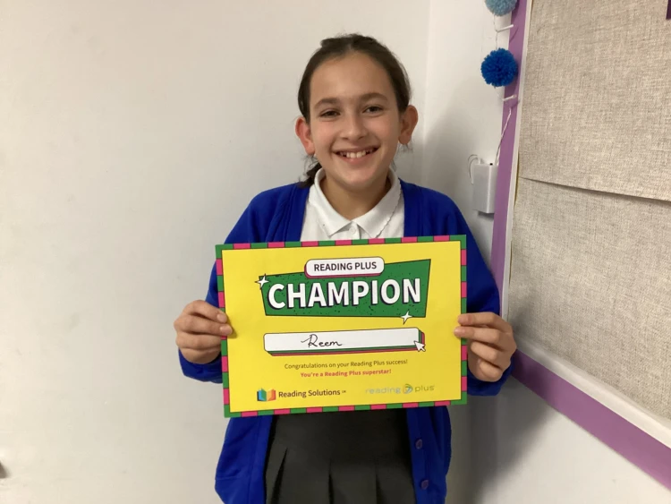 Child holding a Reading Plus Champions certificate 